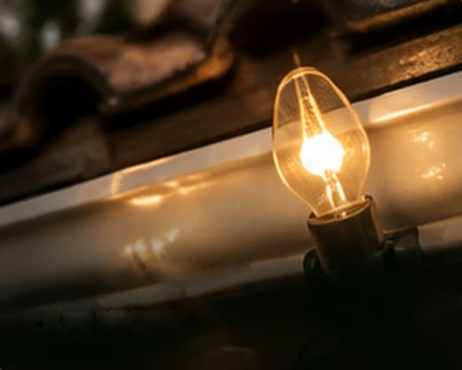 Close-up of a glowing vintage bulb on a gutter line
